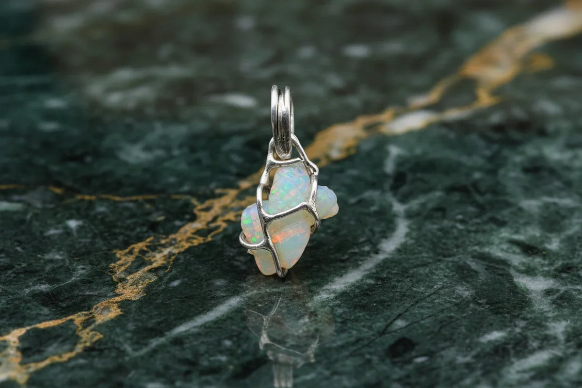 Handcrafted opal pendant in silver wire setting on green marble background