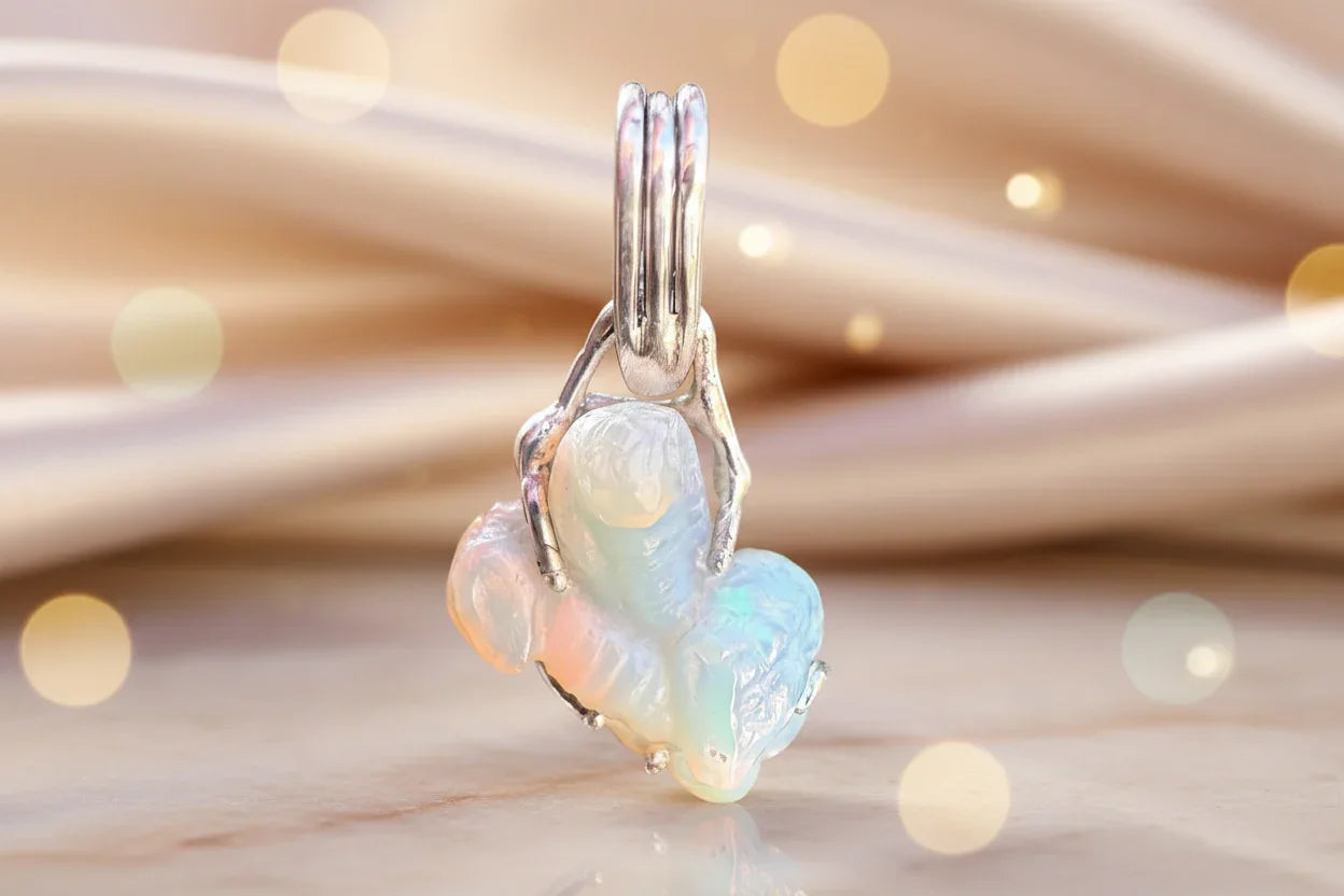 Handcrafted silver and opal pendant with iridescent colors on a neutral background
