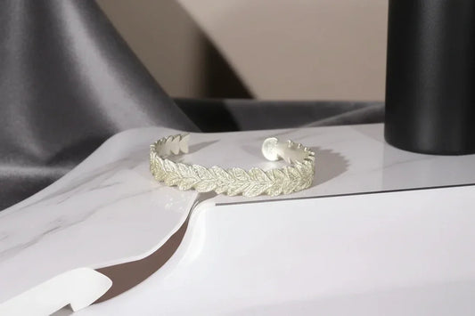 Handcrafted silver leaf cuff bracelet on a marble surface, elegant artisan jewelry