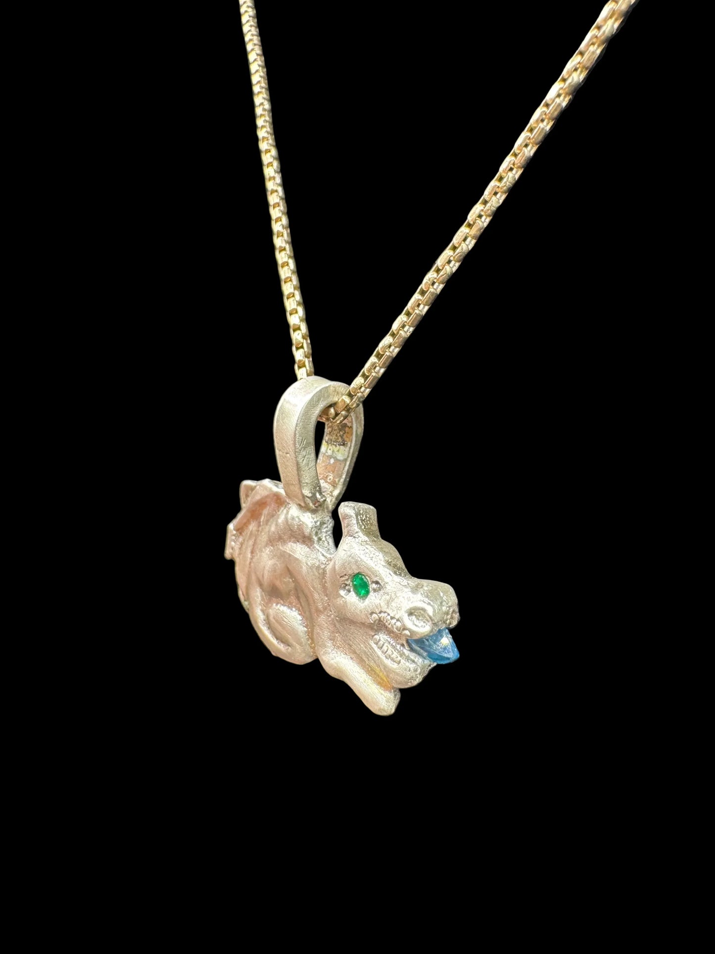 Gold handcrafted dragon pendant necklace with green gemstone eye and blue detail on black background