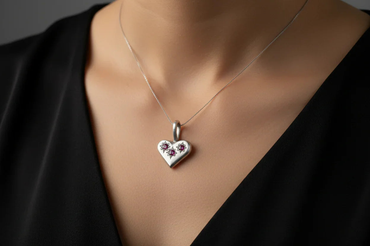 Handcrafted silver heart pendant necklace with floral design on woman in black top