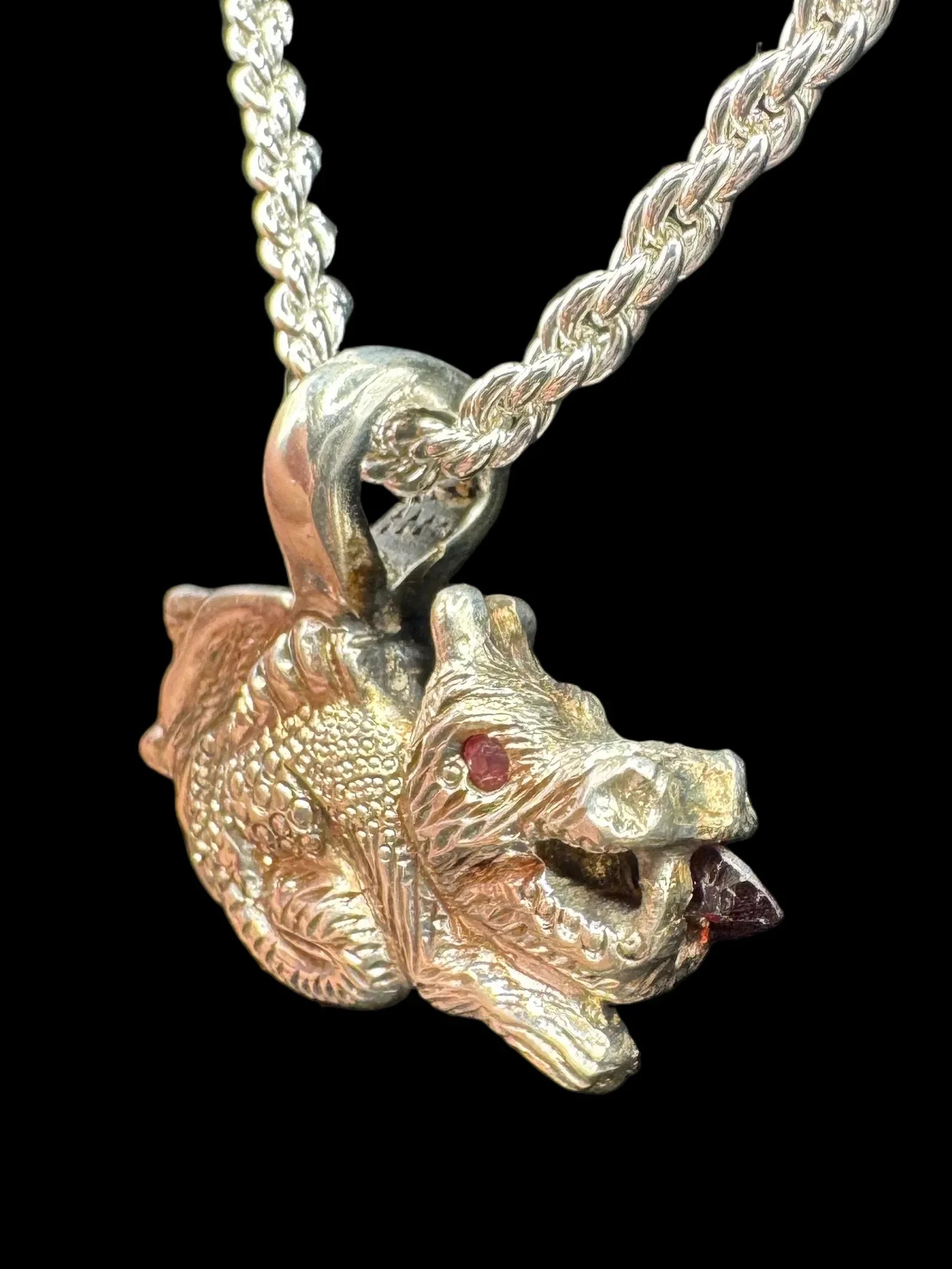 Handcrafted silver dragon head pendant with gemstone eye on braided chain, black background