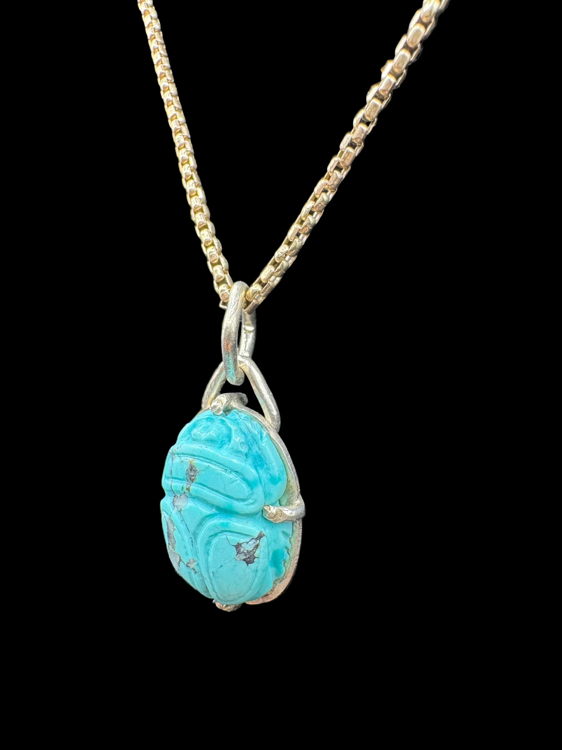 Turquoise scarab pendant necklace with gold chain on black background