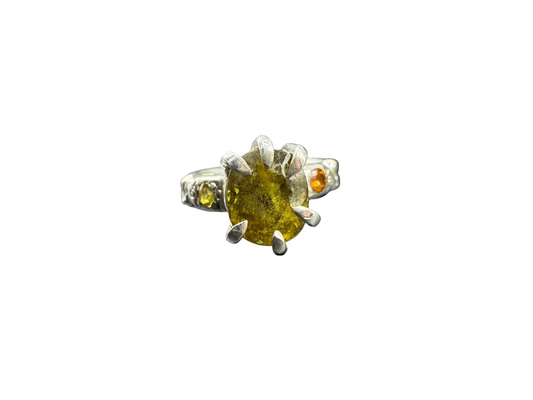 Close-up of a silver ring with a green gemstone on a metallic surface