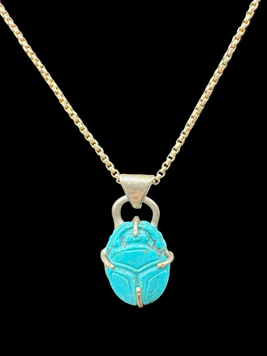 Turquoise scarab pendant necklace with silver chain on black background