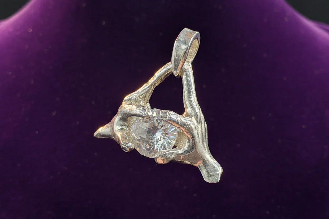 Silver skeleton hands pendant holding a large round gemstone against a purple background