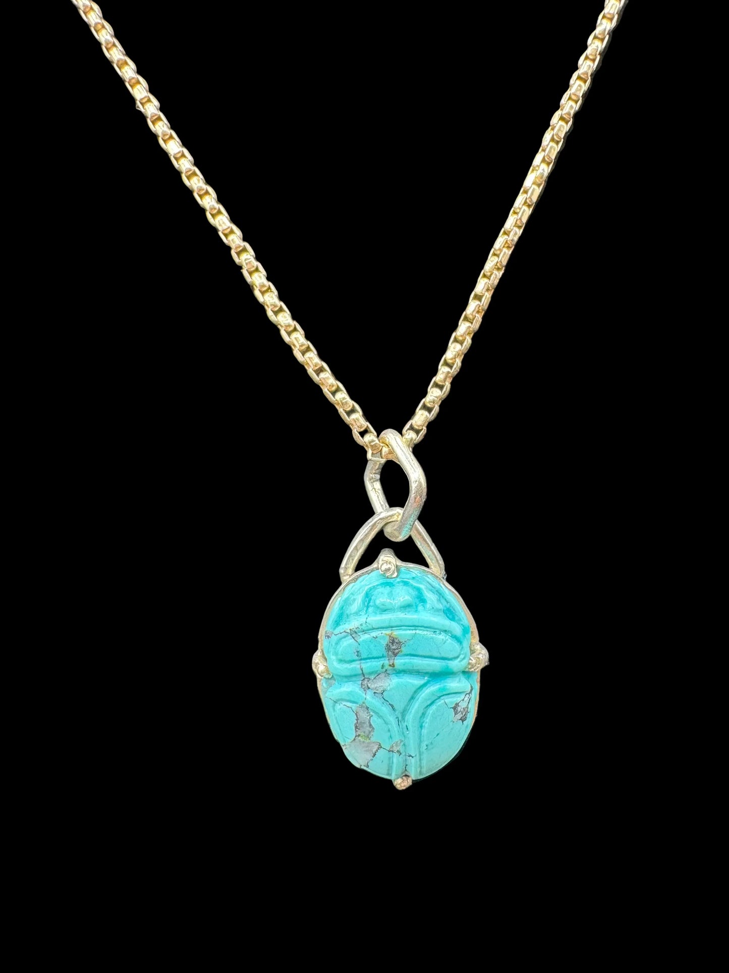 Gold chain necklace with turquoise scarab pendant on black background