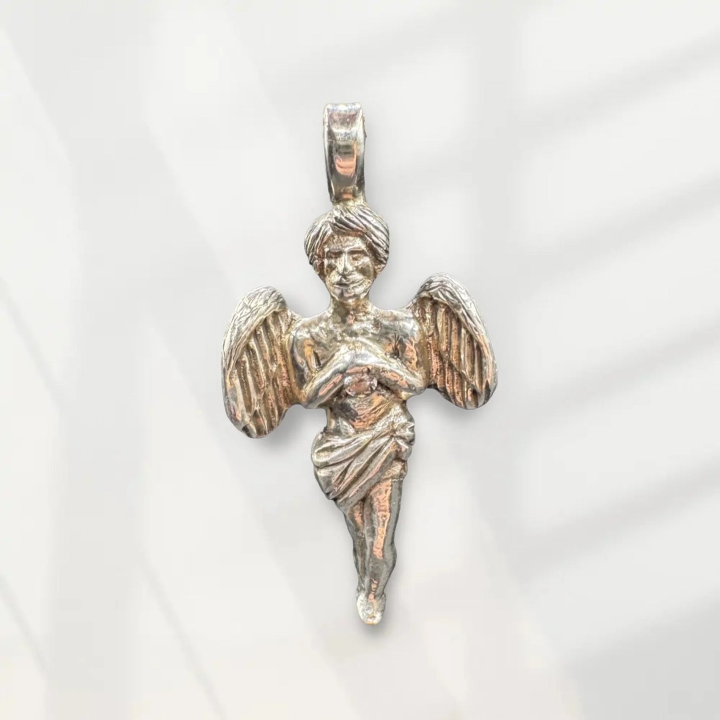 Handcrafted silver angel pendant with detailed wings and robe on a light background