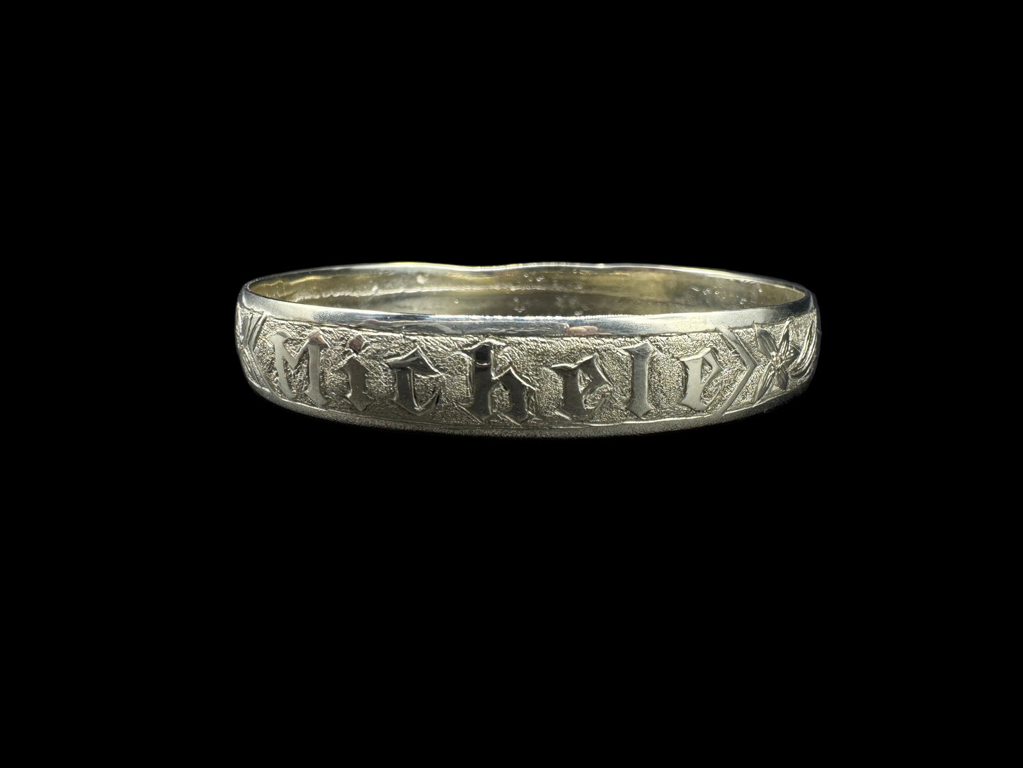Gold Bangle with engraved text on a black background