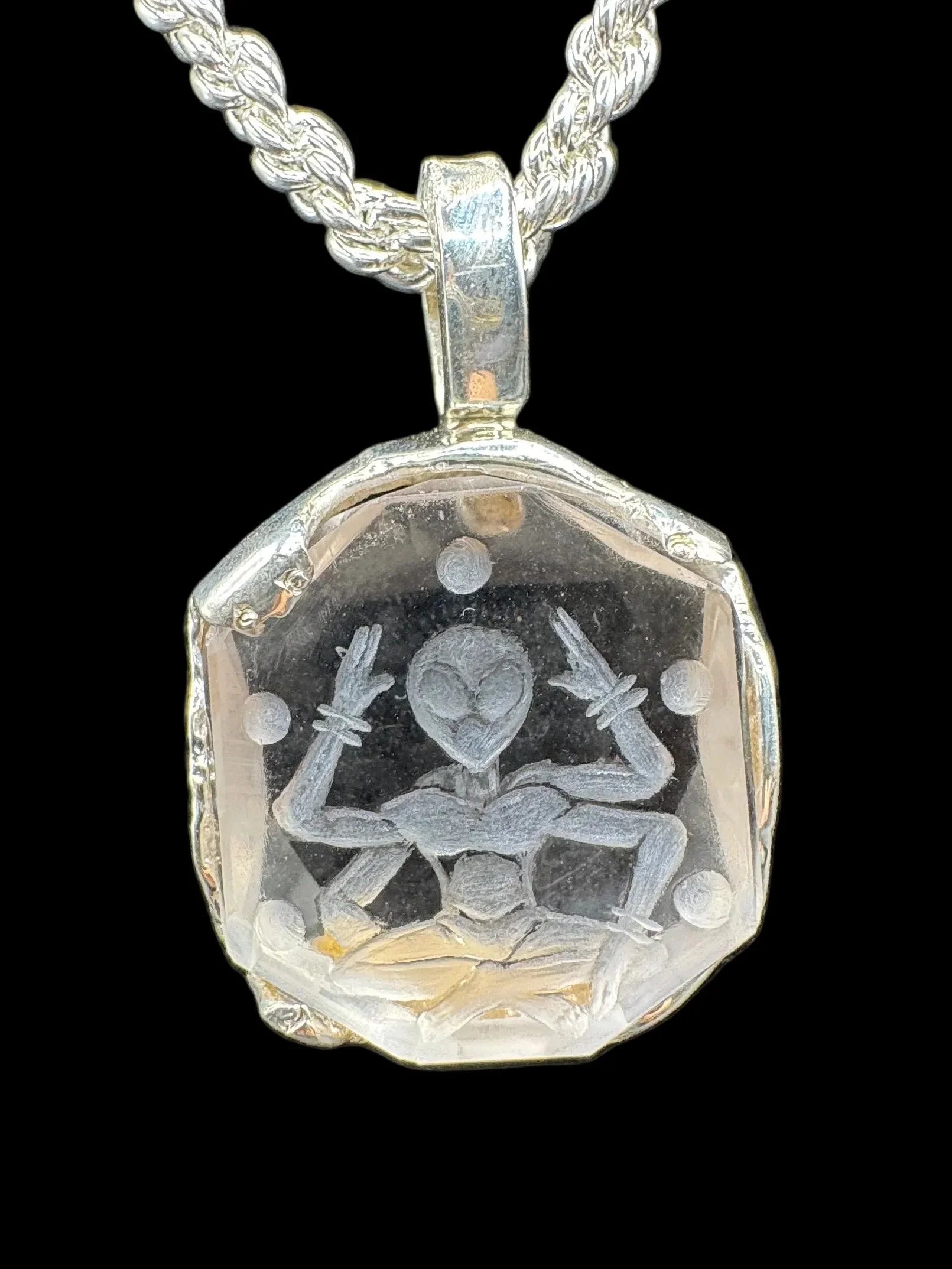 Handcrafted silver pendant with engraved figure, geometric border, and braided chain on black