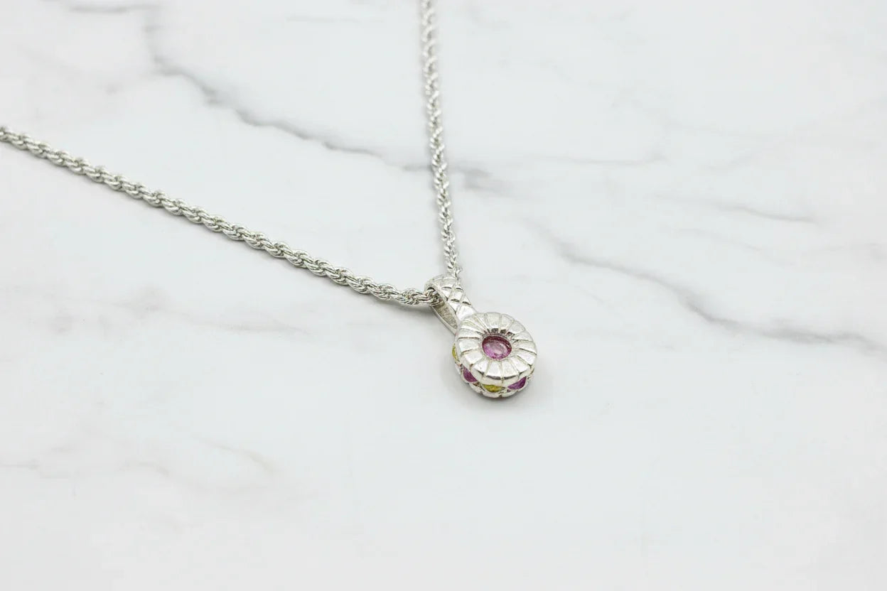 Handcrafted silver necklace with round pink gemstone pendant on marble background