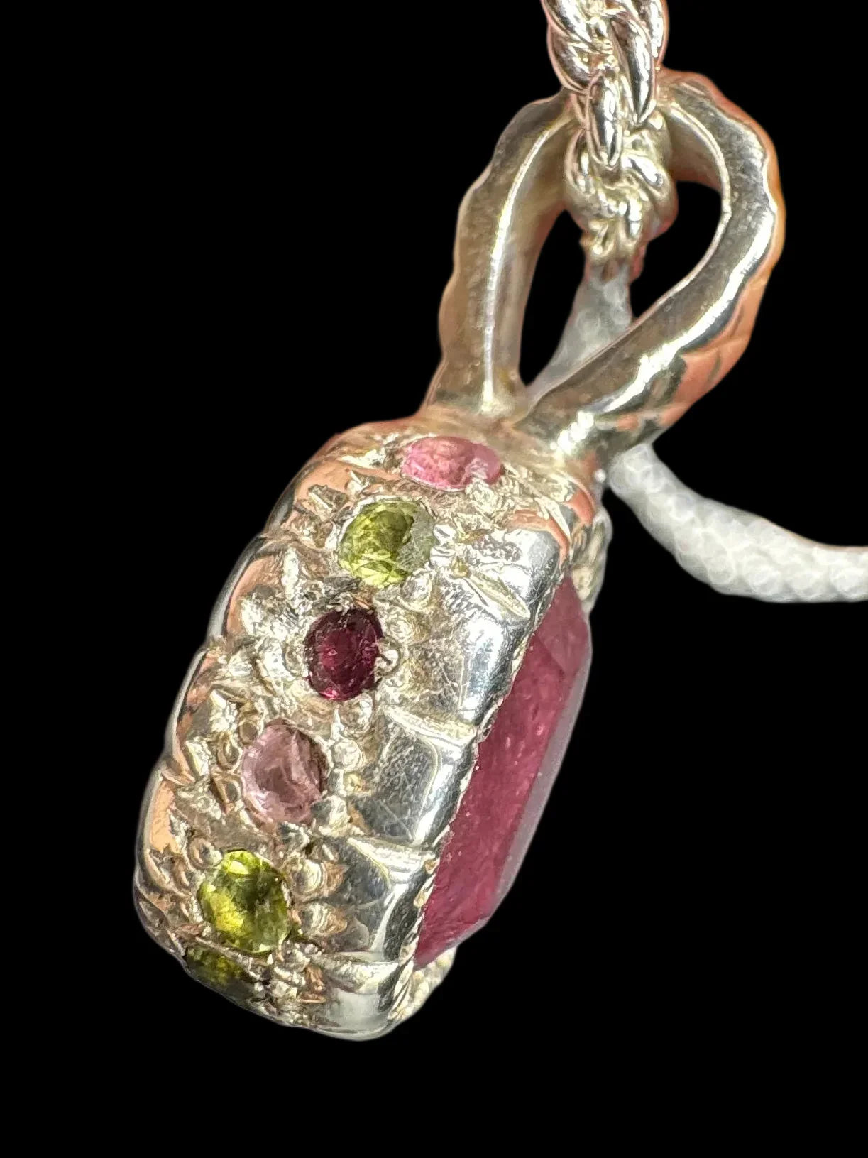 Handcrafted silver pendant with multicolored gemstones and textured detailing on a chain