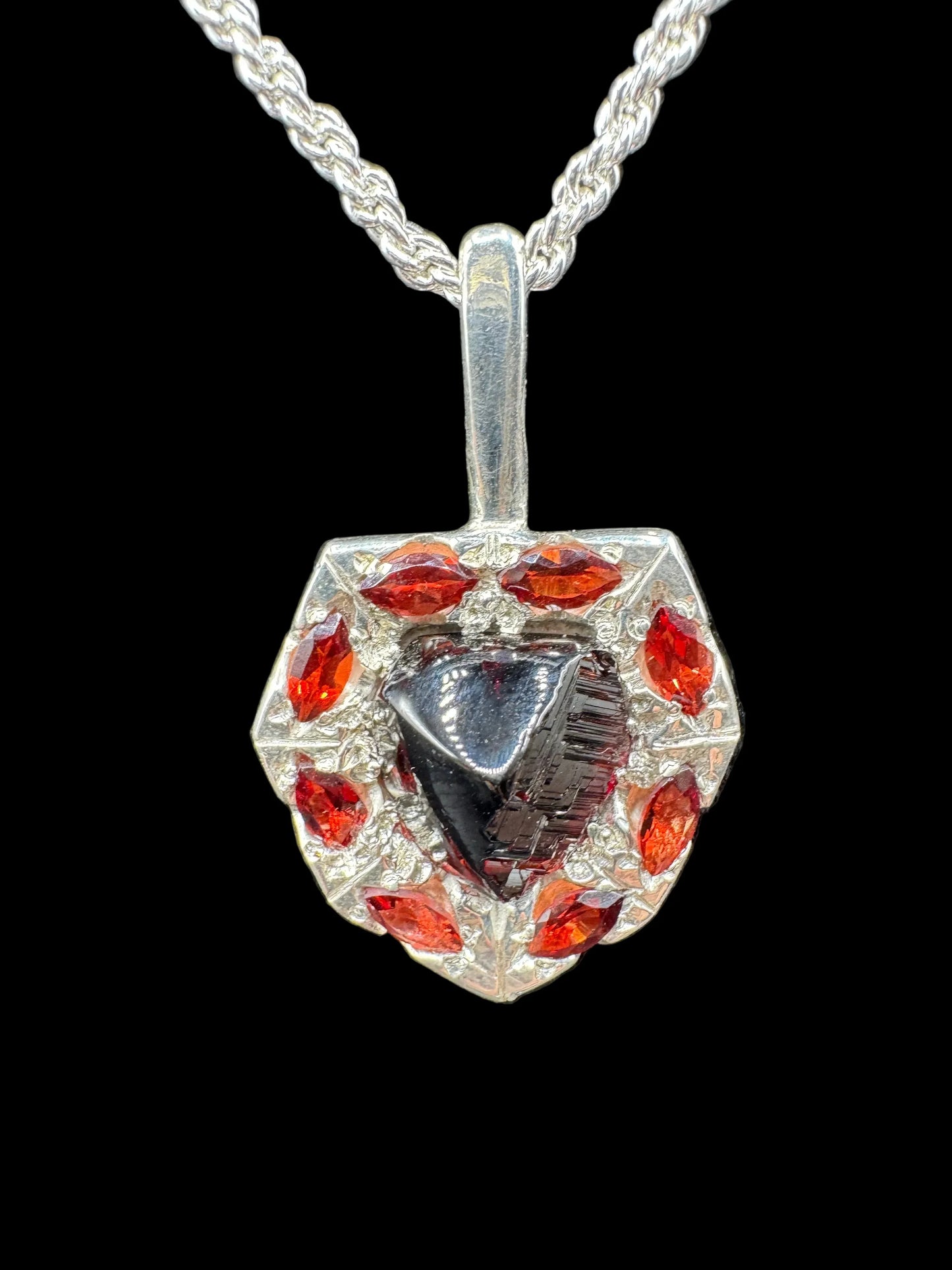 Handcrafted silver pendant with a black triangular gemstone and red marquise gemstones on a chain
