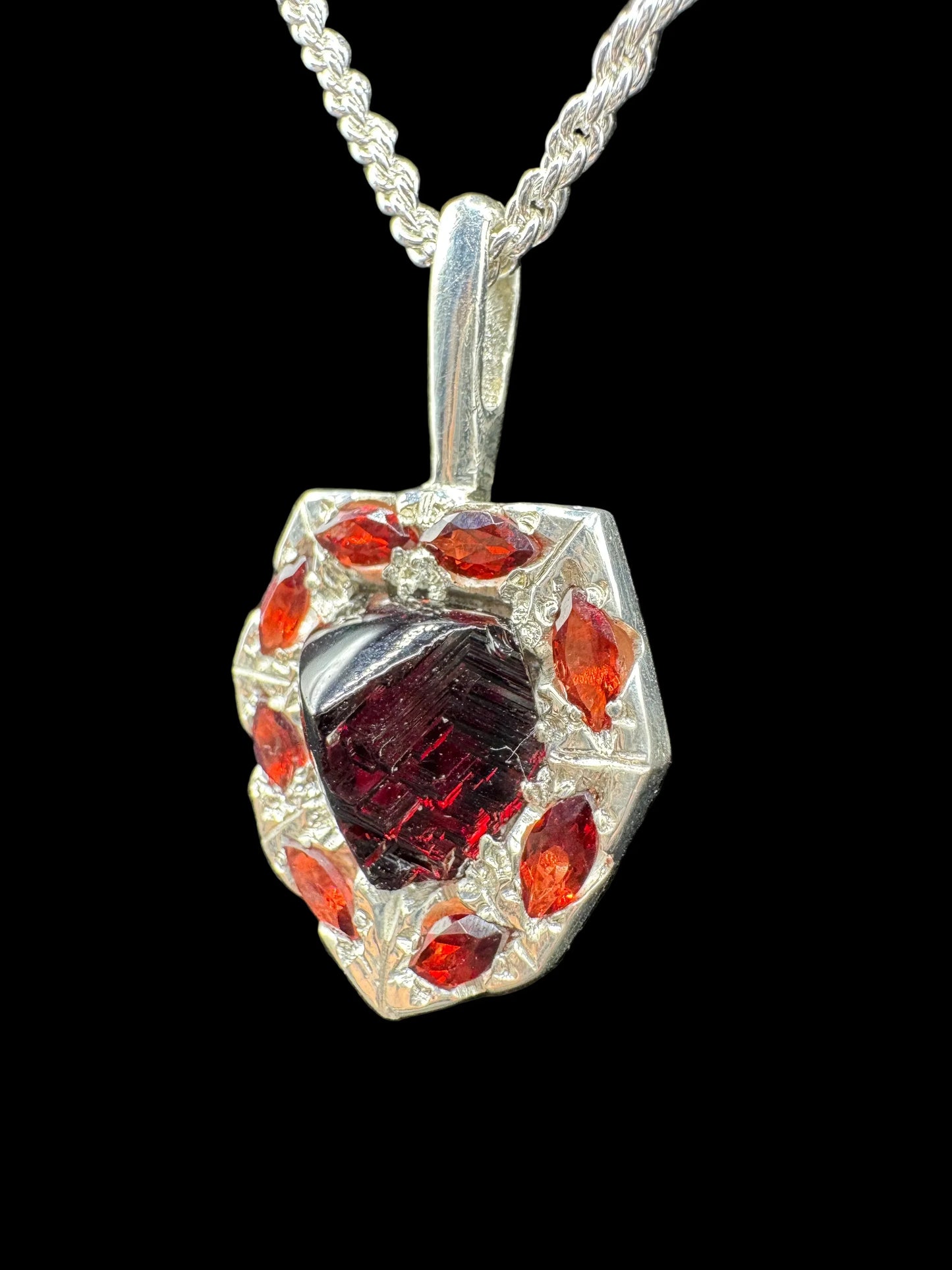 Handcrafted silver pendant with red gemstone centerpiece and orange accent stones on chain