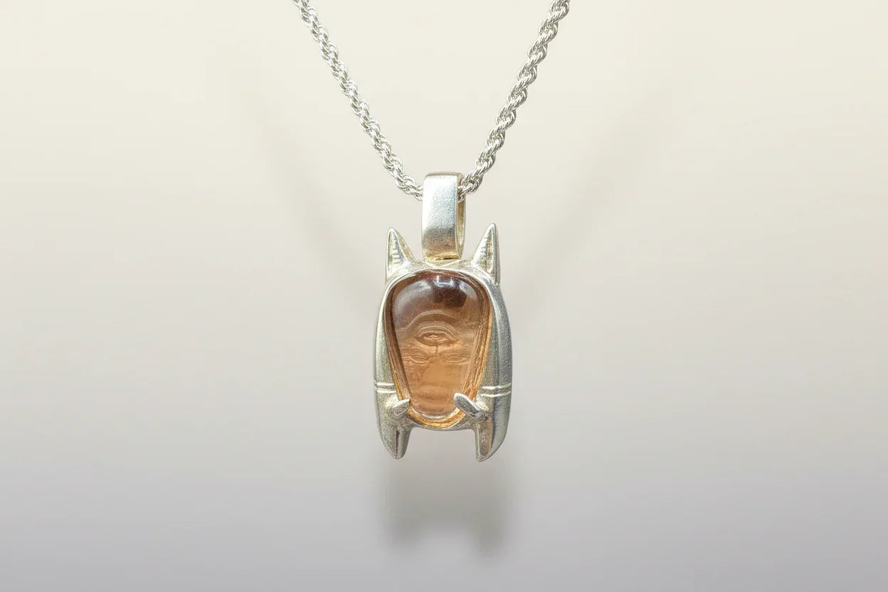 Handcrafted silver necklace with carved gemstone pendant featuring an abstract face design