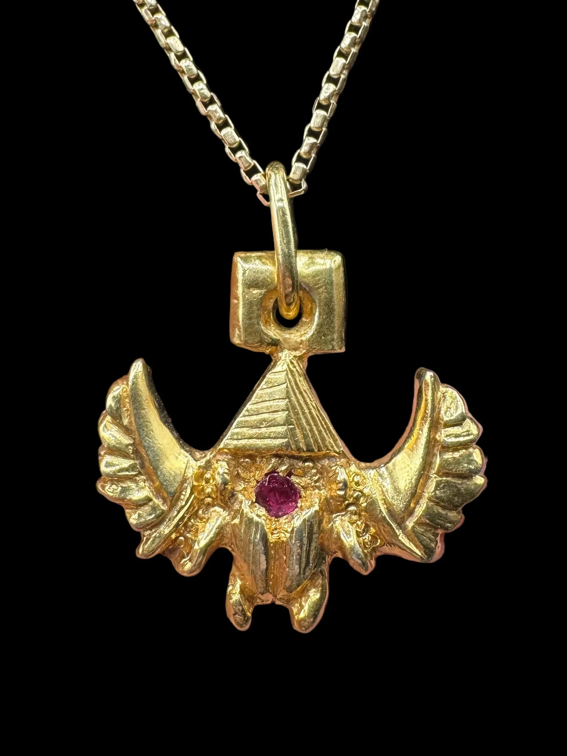 Handcrafted gold pendant with ruby gemstone and winged design on a chain necklace