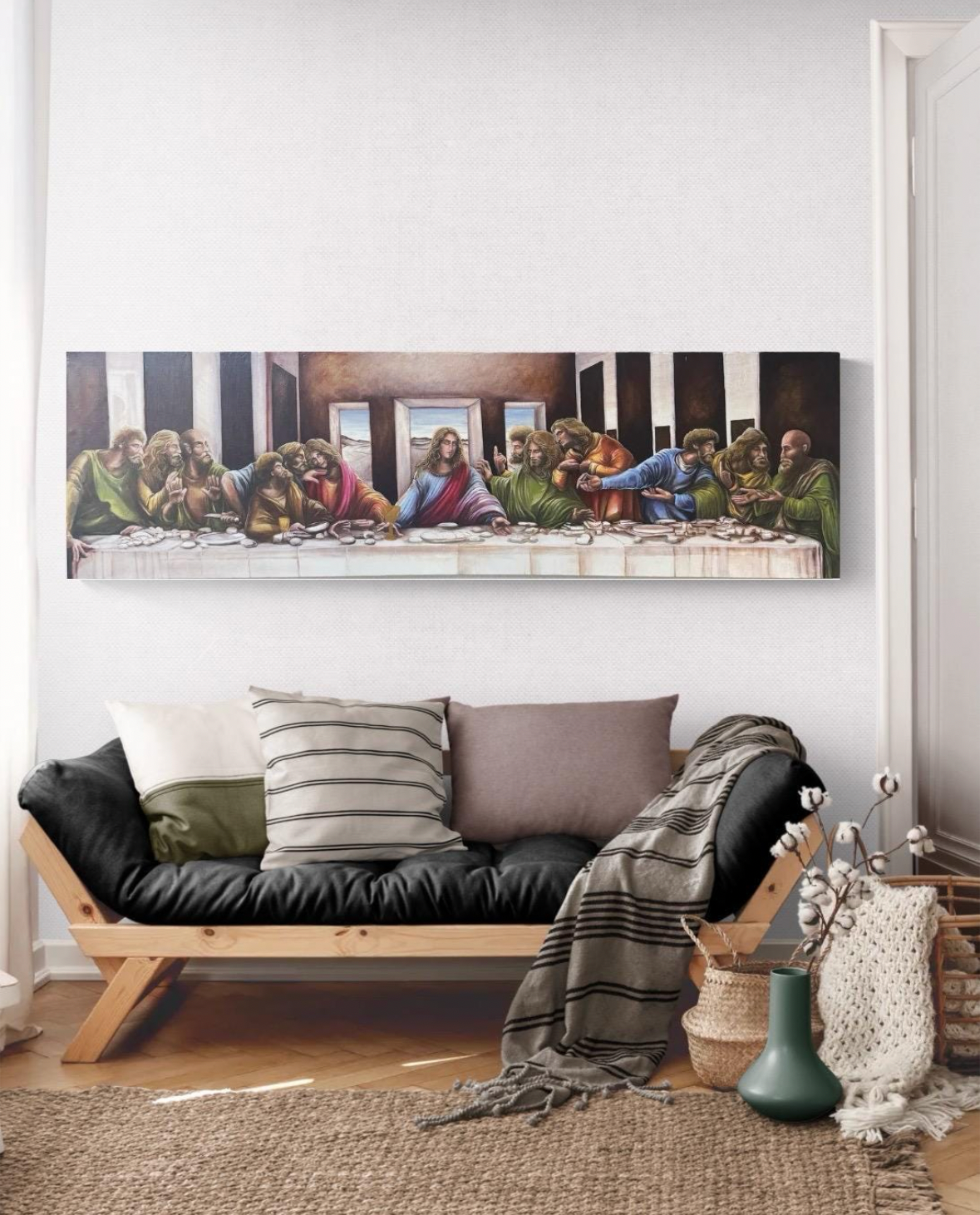 Living room with a black sofa, decorative pillows, and a painting of 'The Last Supper' on the wall.